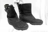 Pair of black UGG Event waterproof boots shown side by side, highlighting the side zipper and buckle strap.