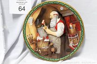 Close-up photo of circular plate featuring Norman Rockwell's 'Santa's Workshop' relief scene with Santa crafting toys in the workshop.
