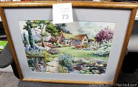 Full view of the framed print showing the cottage scene with water lilies, in wooden frame with matting.