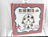 Box of ferris wheel cupcake server with red and white striped sides and colorful ferris wheel image holding cupcakes