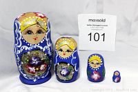 Four blue wooden Russian nesting dolls arranged in descending size order with a MaxSold paper label.