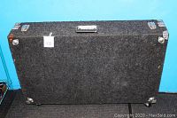 Closed DJ CD road case against blue background, showing top and one side with handle, metal latches, and carpet covered surface