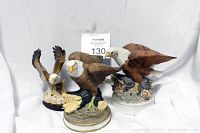 Front and side view of three porcelain eagle figurines on display with lot number.