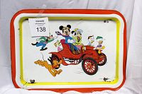 Front side of the vintage folding serving tray showing the colorful print of Disney characters Mickey Mouse, Minnie Mouse, Pluto, Goofy, Donald Duck, Huey, Dewey, and Louie riding a red car with yellow and red borders.