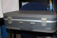 Closed view of the gray hard suitcase with metal latches and handle. "Airplane by Neevel" brand label visible on front.
