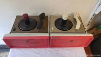 Photo showing front and top views of two vintage RCA turntables side by side, highlighting the tonearms, spindles, and speaker grills.