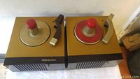 Pair of vintage RCA Bakelite turntables placed side by side showing top view with red spindle knobs and tonearms.