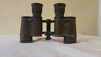 Front view of the vintage military binoculars showing the textured exterior and center adjustment mechanism.