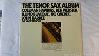 Front cover of 'The Tenor Sax Album' double jazz vinyl album featuring artists Coleman Hawkins, Ben Webster, Illinois Jacquet, Ike Quebec, and John Hardee. Cover shows saxophone image and bold text.
