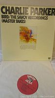 Front cover of Charlie Parker vinyl double album 'Bird/The Savoy Recordings (Master Takes)' showing artwork and album title with one vinyl record partially visible below.
