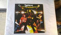 Front cover of Whitesnake live double vinyl album showing band performing on stage with colorful lights and the title.