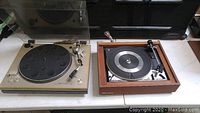 Two untested turntables side by side on a table, Sony PS-3300 on left with silver body, Dual 1214 on right with wood finish and dust cover.