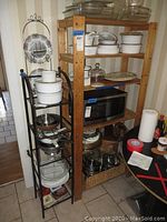 Photo of both shelving units side by side with kitchen items on shelves for scale, showing the taller wood shelf and narrower black metal shelf.