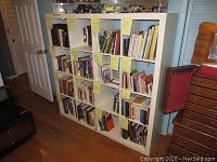 Full frontal view of the white laminated shelving unit filled with books and tags on compartments.