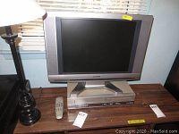Front view of Sylvania TV on top of Philips player with remote beside it