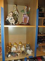 Shelves with two clown figurines, a baby holding an 8 ball, and various small ceramic animal figures including chicks, ducks, rabbit, cat, and bird.