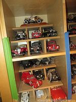 Overall shelf view showing multiple die-cast model cars and trucks on wooden shelving