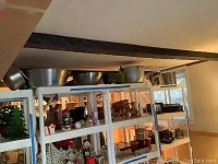Wide view of shelf displaying several metal kitchenware items including stock pots, bowls, kettle, and planter
