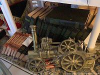 Photo showing classic hardcover books including Compton and Bedtime Stories with a Spanish English dictionary and metal steam engine wall hanging in front.