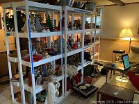 Four white plastic shelving units lined up, filled with various decorative objects but shelves themselves are clean and solid.