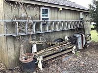 Full view of aluminum extension ladder leaning against the side of a house, showing length and condition.