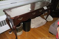 Full view of Thomasville wooden sofa table showing dimensions, shape, two drawers with brass handles, curved edges and cabriole legs, placed in a living room setting.