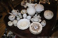 Full view of the assorted teapots, pitchers, serving dishes, plates, bowls, and cups on a wooden table.