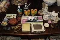 Photo of assorted items on wooden table including candles, figurines, teapots, frames, and decorative items