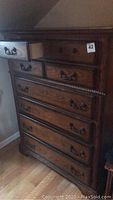 Full view of eight drawer wooden highboy dresser showing medium brown finish and metal drawer handles, one handle missing