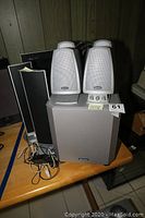 Photo showing 4 Boston Acoustics BA 7800 satellite speakers and the subwoofer on a wooden table