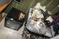 Full view of lot with Danby mini refrigerator on floor next to a small black stool holding a wooden knife block and a collection of kitchen appliances and utensils on a metal cart.