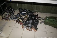 Eight pairs of in-line roller blades displayed on a floor next to a green golf bag containing golf clubs.