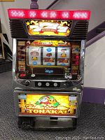 Front view of slot machine with illuminated marquee and lower graphic panel