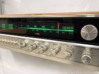 Close-up view of front tuning dial and audio control knobs showing AM/FM frequency range and various control knobs for bass, treble, balance, volume, and selectors.