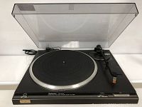 Full view of the Technics turntable with transparent dust cover, tonearm, and power cord visible.
