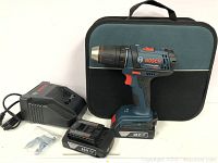 Full kit showing cordless drill, two 18V batteries, charger, and soft carrying case.