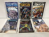 Six Teenage Mutant Ninja Turtles comics in protective sleeves displayed upright and side-by-side.