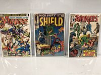 Three comics in protective sleeves shown upright: Avengers issue with Yellow Claw, Nick Fury #1 with S.H.I.E.L.D. logo, another Avengers with a gunslinger theme.