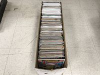 Long cardboard box filled with a stack of comic books, spines facing up.