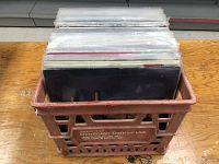 Red plastic Dominion Dairies Ltd milk crate filled with vinyl records in sleeves