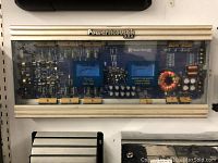 Top view of PowerAcoustik car amplifier showing transparent cover and internal circuit components.