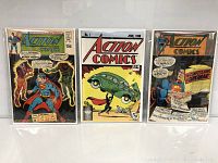 Three Action Comics comic books from the lot, showing covers. Includes Action Comics No.1 reprint on center, and two other issues on sides with colorful vintage Superman artwork.