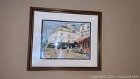 Photo of framed print showing a detailed outdoor French cafe scene with people and buildings.