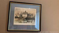 Framed signed chateau scene print displayed against a wall