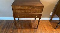 Front view of Drexel wooden secretary desk with green leather top and brass ring-pull drawer handles.