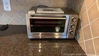 Front view of stainless steel Cuisinart convection toaster oven on kitchen counter.