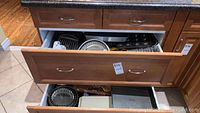 Photo showing open drawers filled with various bakeware items including cake pans, muffin tins, and a waffle maker.