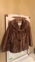 Full frontal view of the brown mink fur jacket hanging on a mirror, showing the collar and button details.