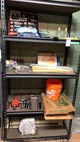 Shelf showing multiple items including tools, heaters, box, orange bucket, and clamps.