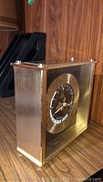 Seiko desk clock front angled view showing glass front, black and gold dial, and metal frame